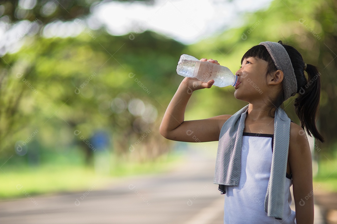 Linda garota asiática bebe água de uma garrafa ao ar livre.