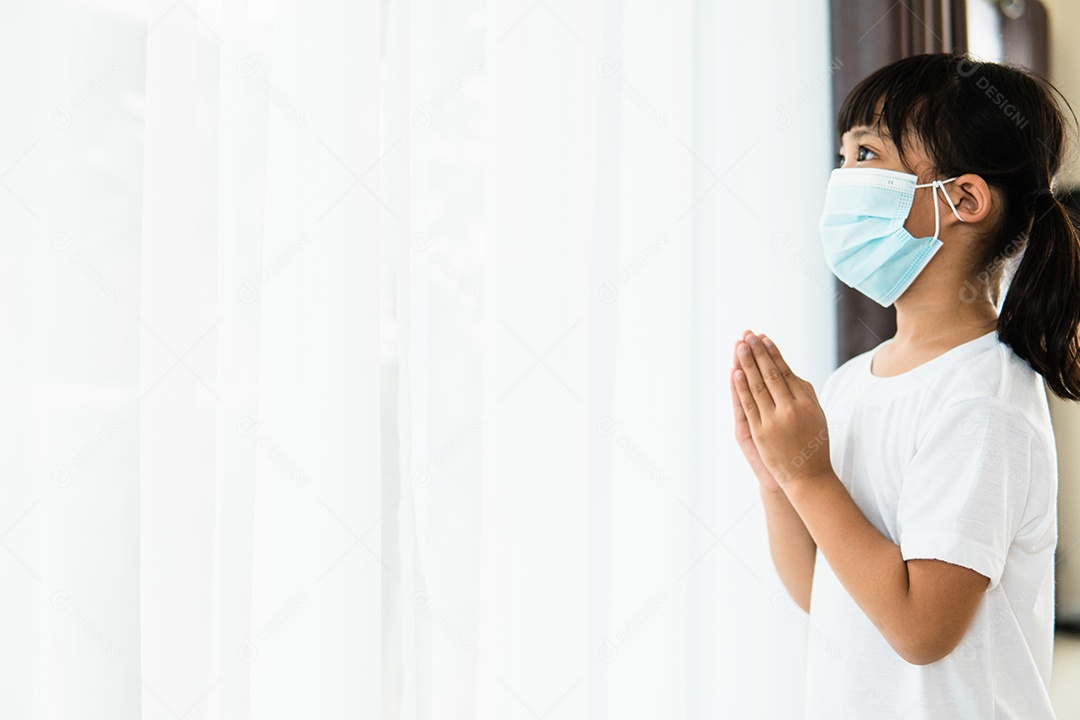 Menina asiática rezando usando máscara para proteger Covid 19