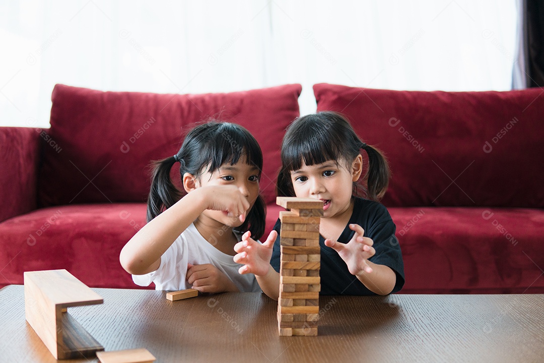 Duas garotas asiáticas jogando pilhas de madeira em casa