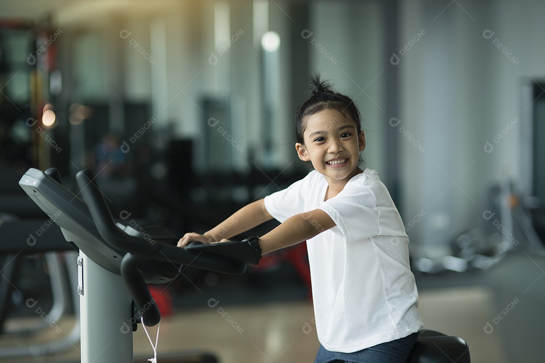 Menina usando bicicleta ergométrica no ginásio. Fêmea de fitness usando bicicleta
