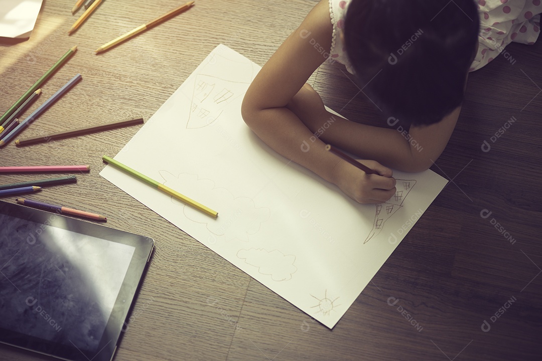 Criança desenhando no chão em papel