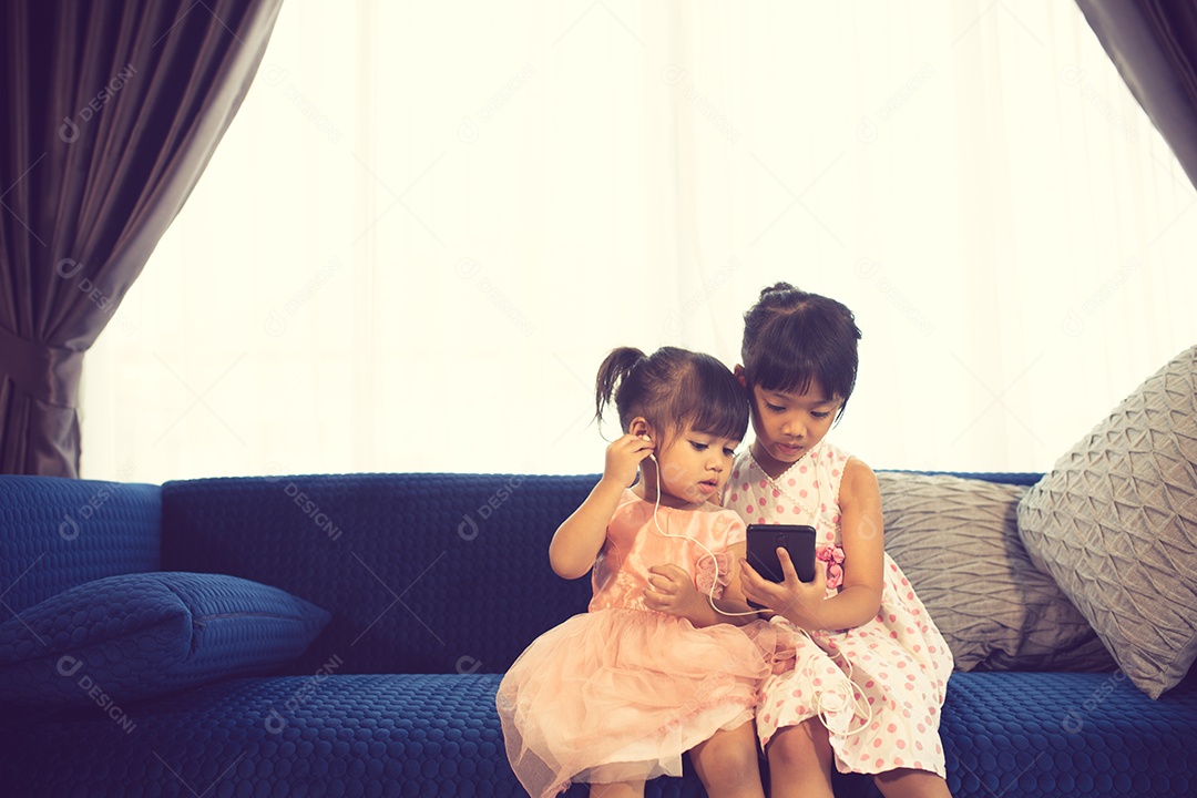 Crianças ouvindo música enquanto estão sentados em um sofá