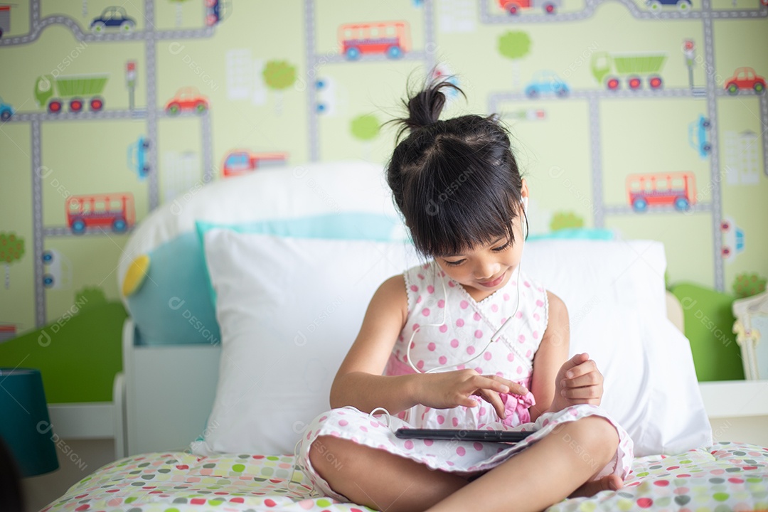 Criança asiática usando fone de ouvido para ouvir música pelo smartphone