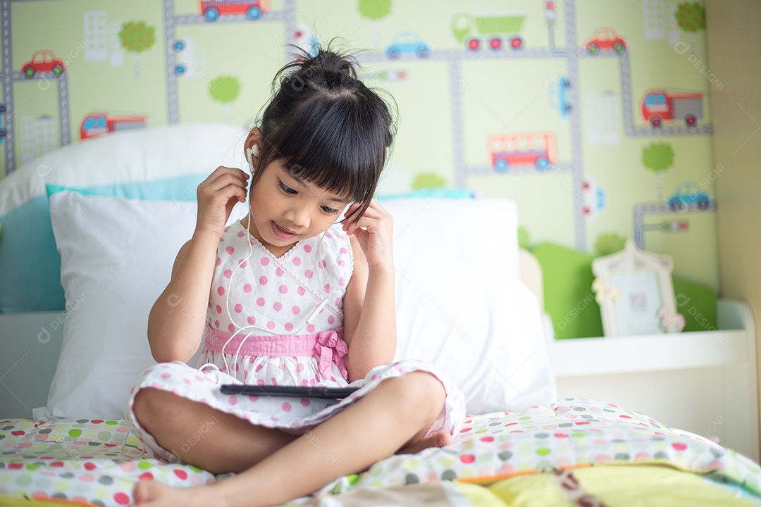 Asian child using headphones to listen to music on smartphone