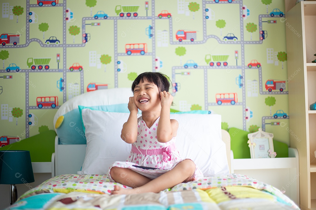 Criança asiática usando fone de ouvido para ouvir música pelo smartphone