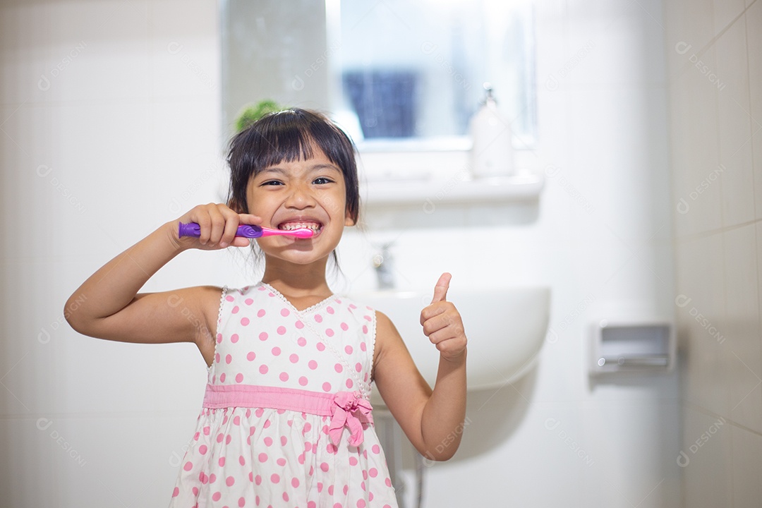 Menina bonitinha limpando os dentes com escova de dentes no banheiro