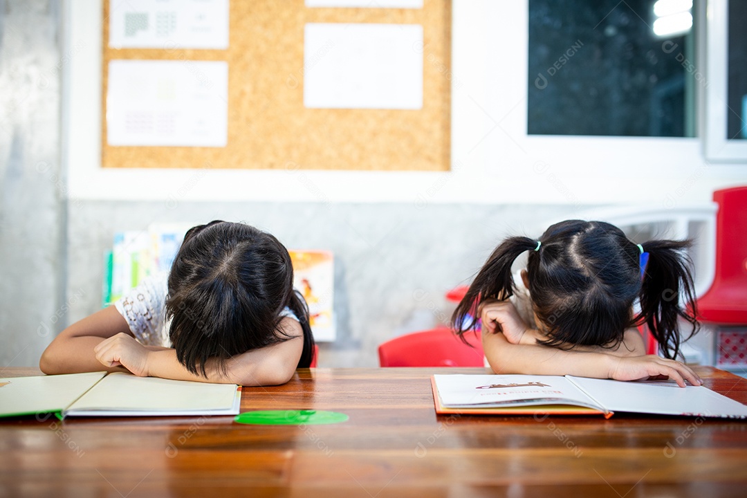 Alunos sonolentos cochilando em mesas em sala de aula na escola primária
