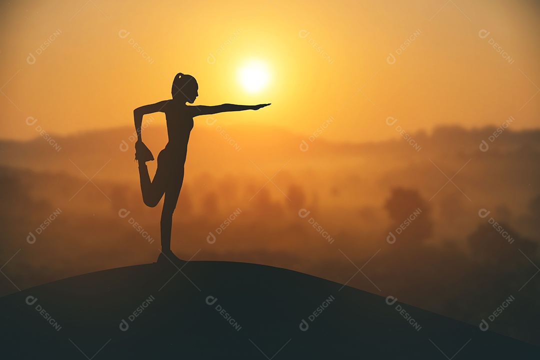 Silhueta jovem praticando ioga ao pôr do sol.
