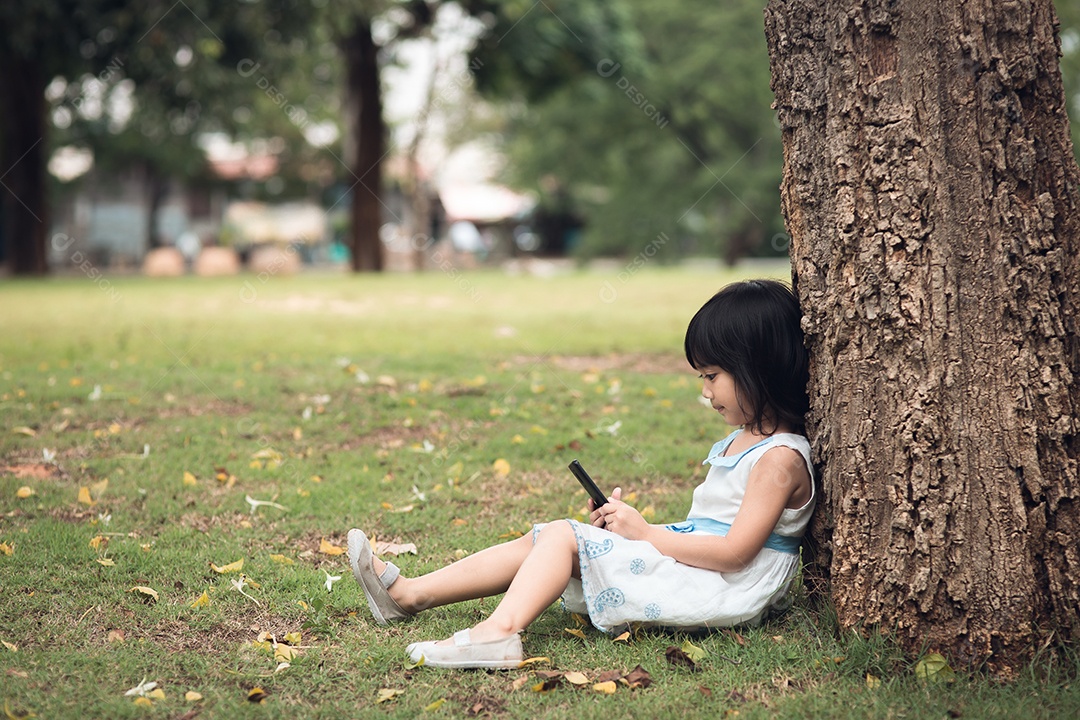 Menina com um telefone celular no parque