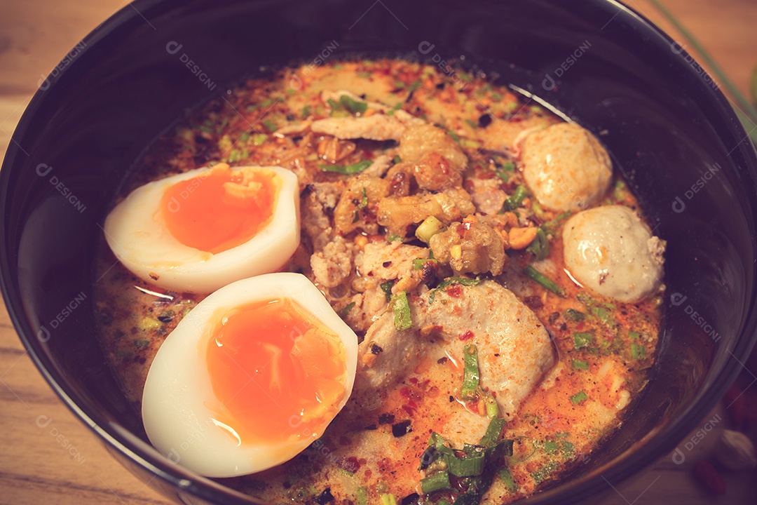 Tigela de macarrão com legumes e ovo cozido na taboa de madeira.