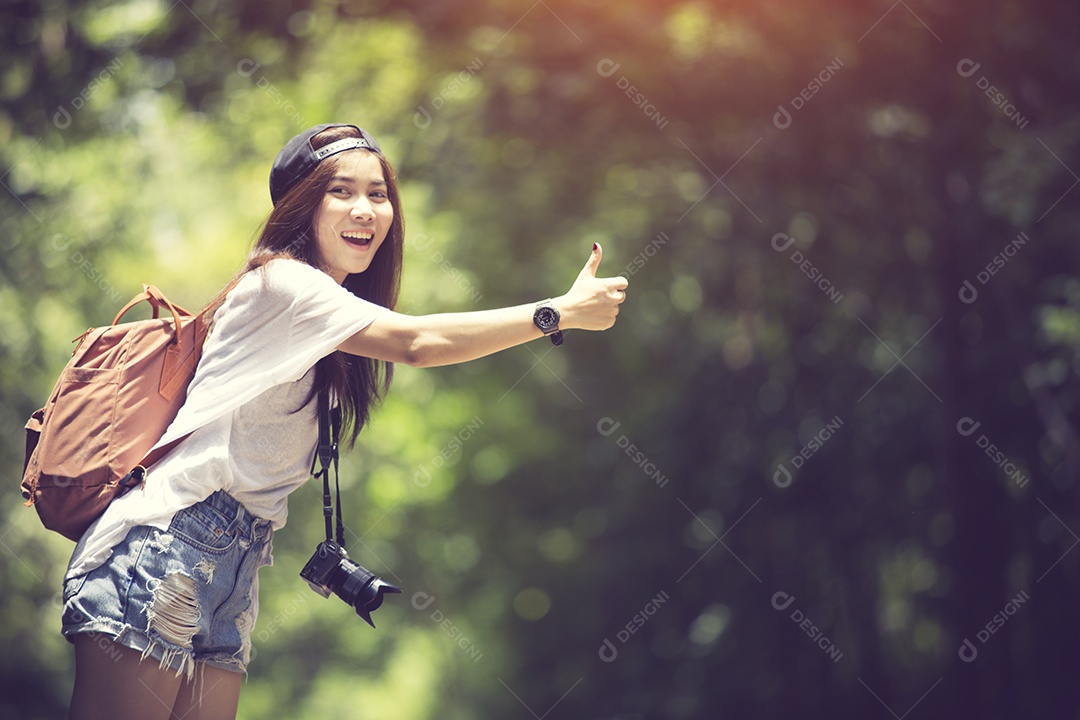 Jovem mulher bonita pedindo carona em pé na estrada cor vintage.