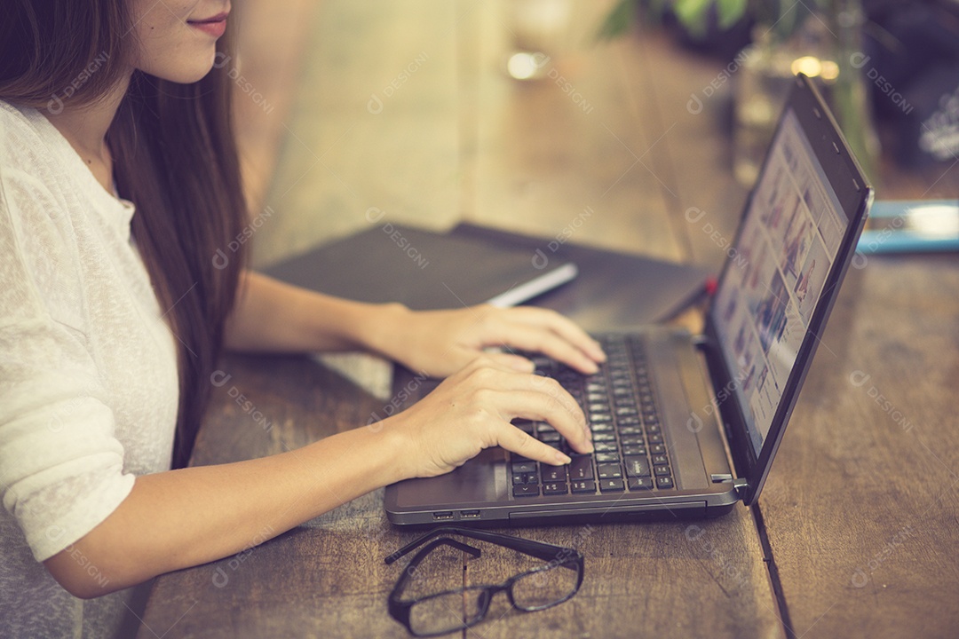 Linda jovem asiática trabalhando em uma cafeteria com um laptop.