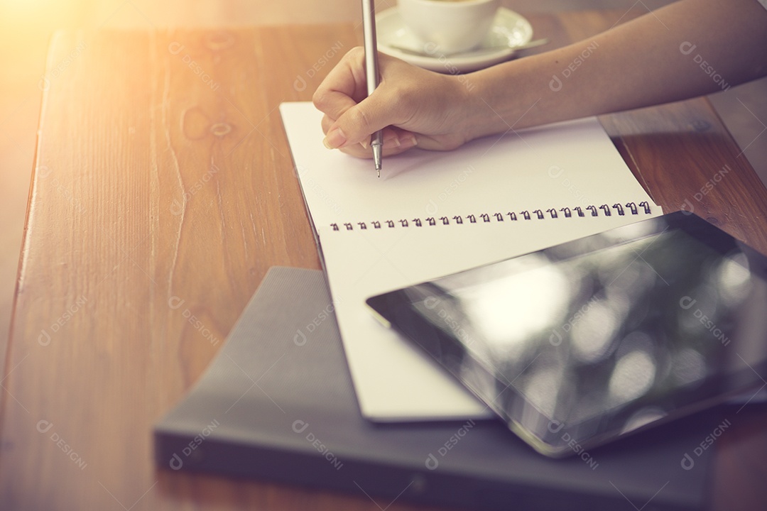 Mão direita escrevendo no caderno de manhã com filme vintage.