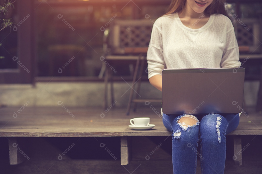 Linda jovem asiática trabalhando em uma cafeteria com um laptop.