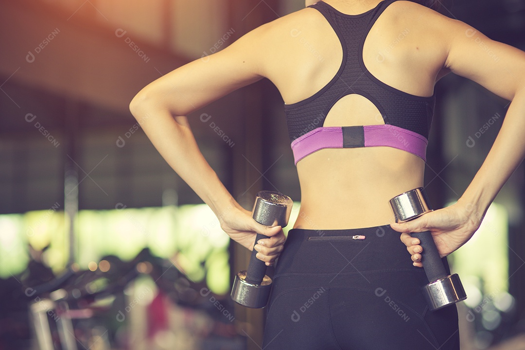 Mulher jovem fitness, execute exercícios com halteres.