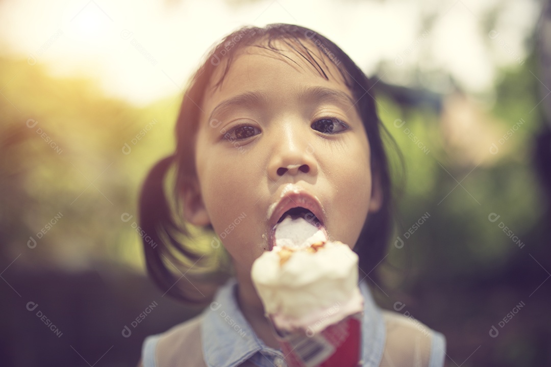 Criança comendo sorvete. Criança encaracolada divertida com sorvete.