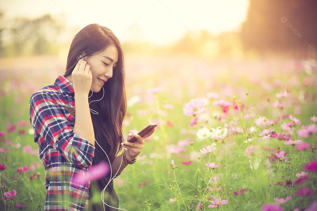 Garota jovem hipster ouvindo música em fones de ouvido em um cosmos.