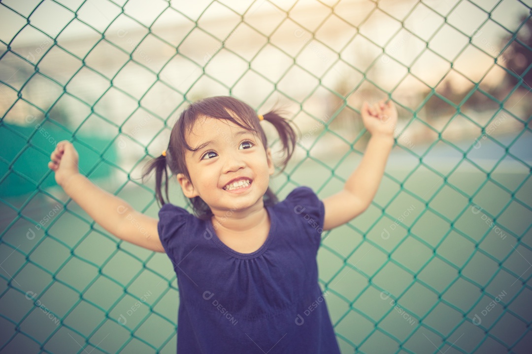 Garota bonita feliz em um campo jogando com picos naturais ao pôr do sol de verão