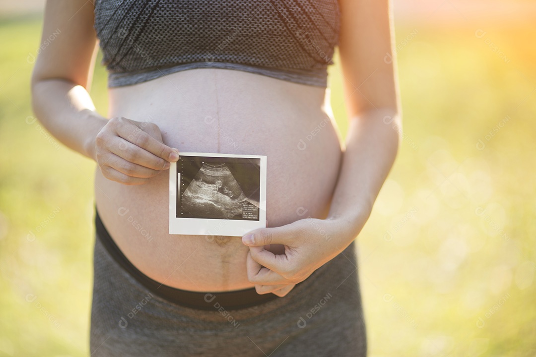Mulher grávida segurando imagem de ultrassom de seu filho