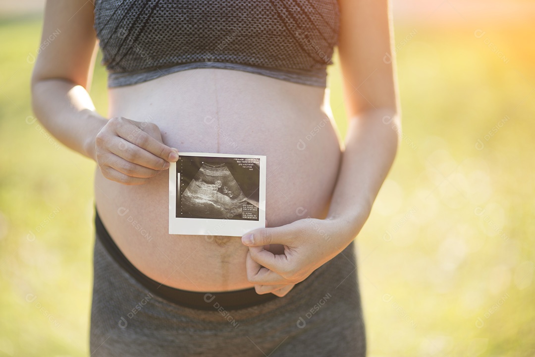 Mulher grávida segurando imagem de ultrassom de seu filho