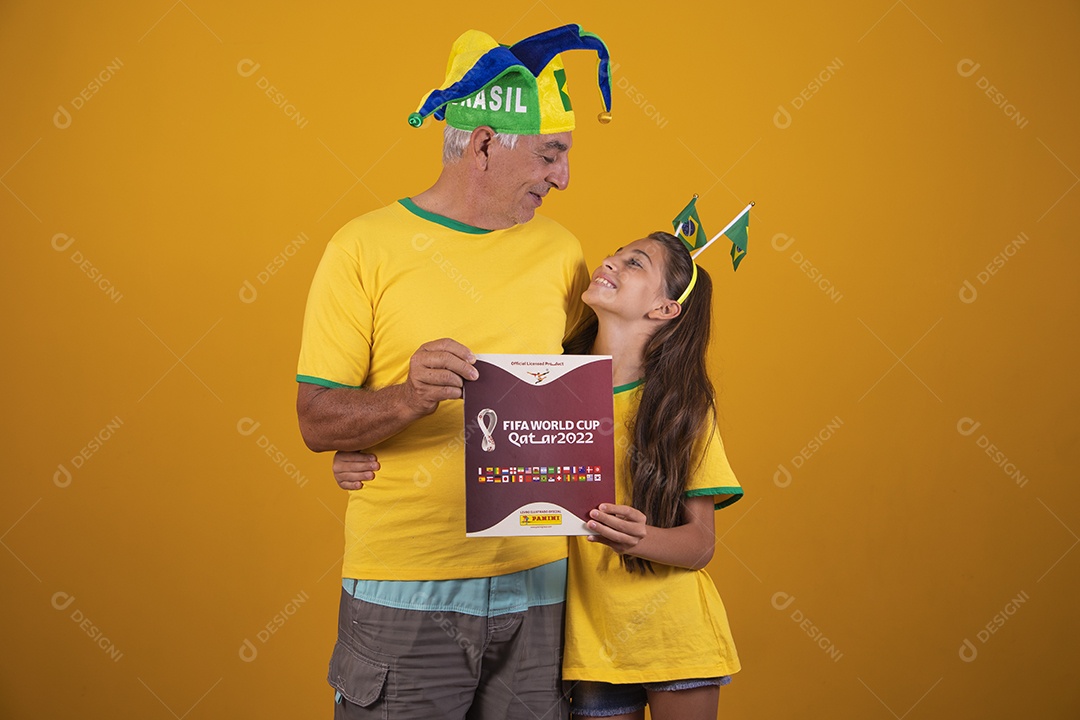 Homem idoso com sua neta torcedores do brasil segurando álbum da copa