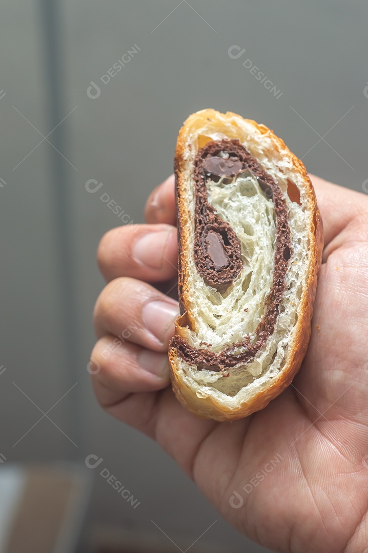 Mãos segurando pão chocolate, croissant de chocolate com fundo branco