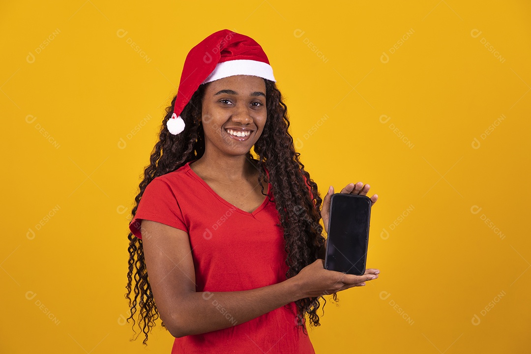 Linda mulher negra segurando celular usando gorro do papai noel Feliz Natal