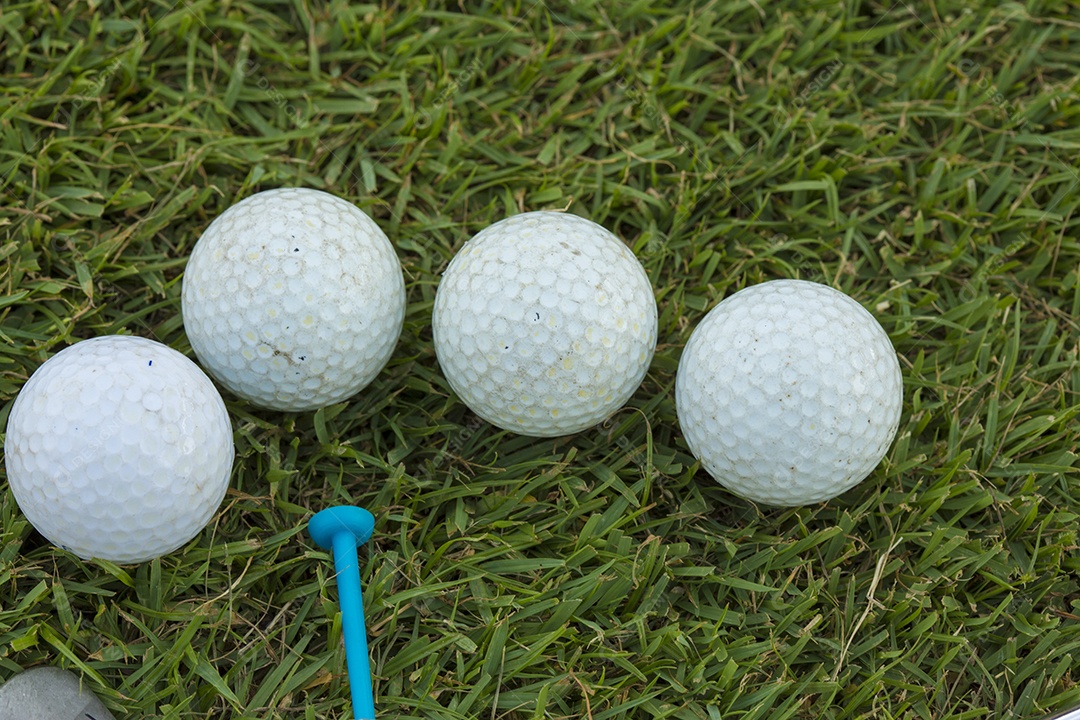 Bola de golfe e clube de golfe na grama.