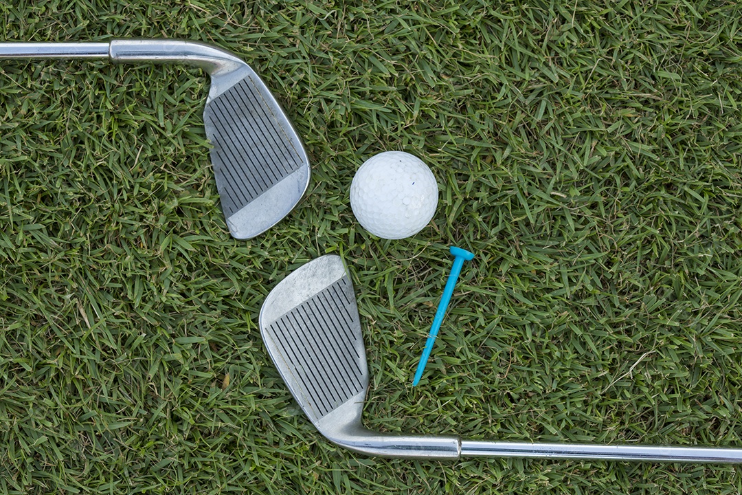 Bola de golfe e clube de golfe na grama.