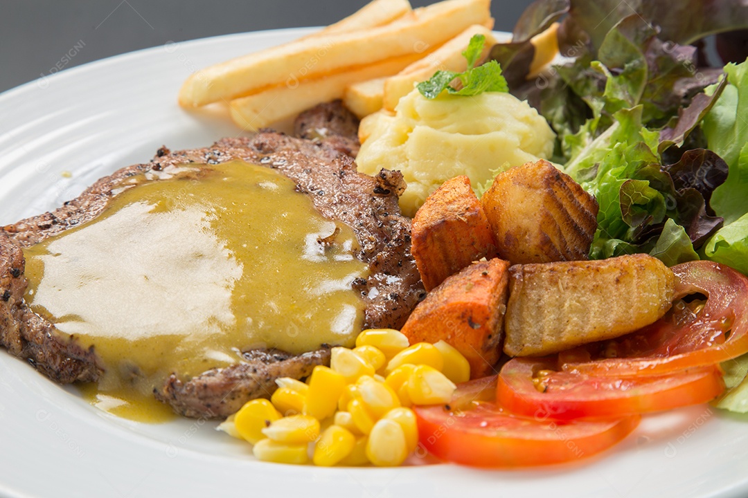 Bife de carne e salada de legumes em um prato.