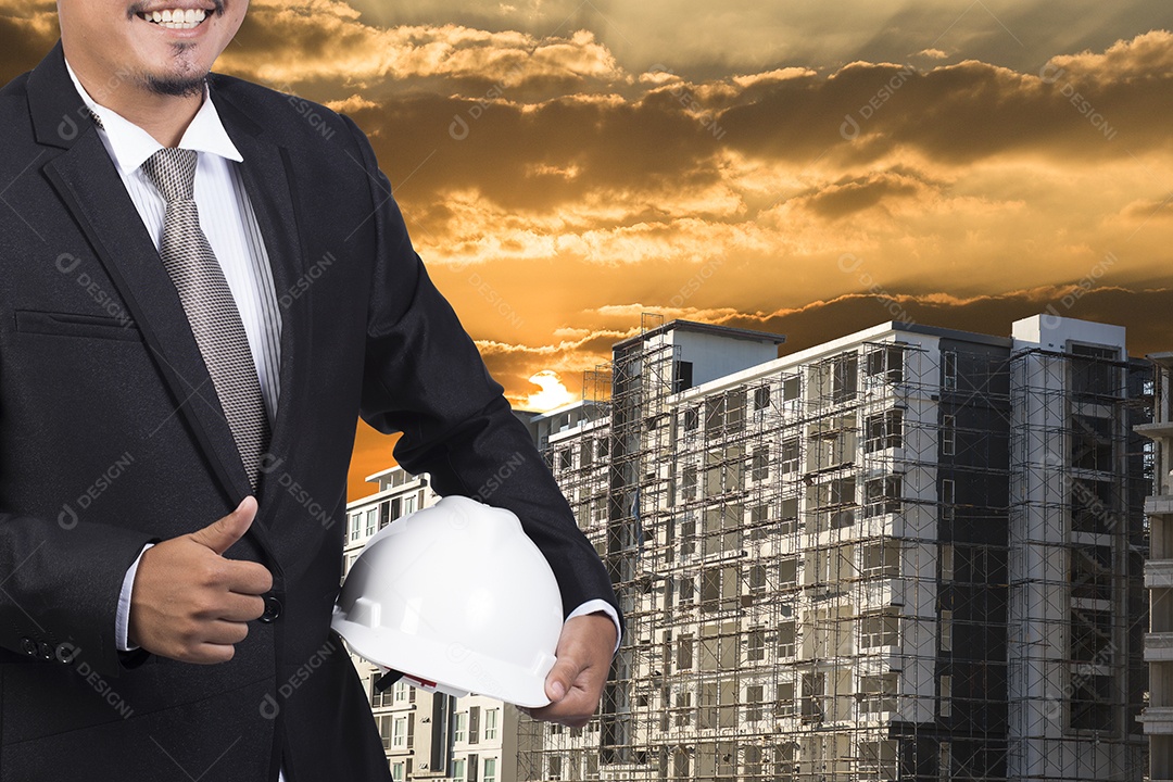 Engenheiro segurando capacete branco para segurança dos trabalhadores em segundo plano.