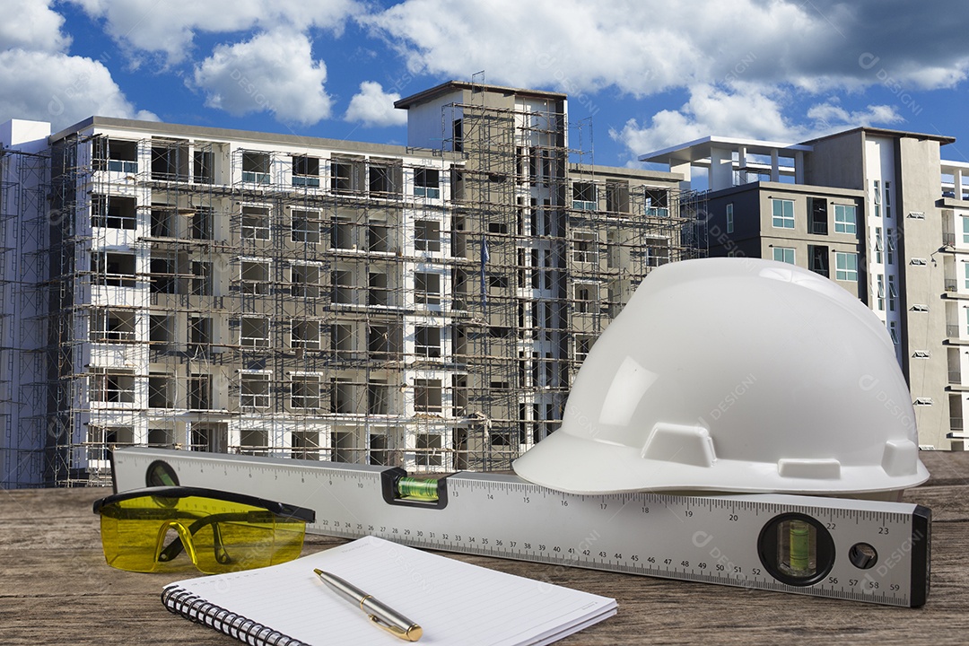 Arquivo de capacete de segurança e planta de arquiteto na mesa de madeira.