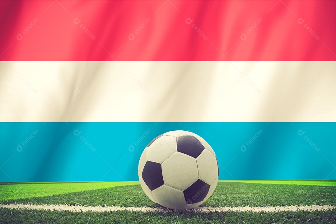 A bola de futebol e a bandeira nacional de Luxemburgo encontram-se no grama verde.
