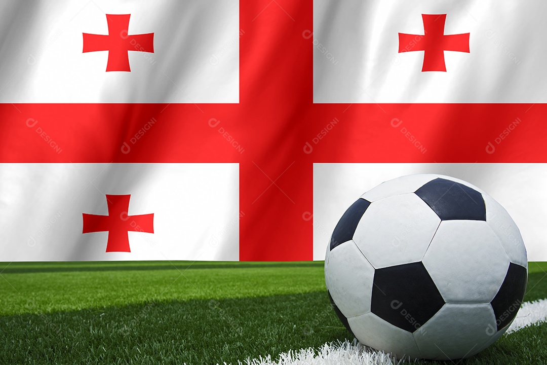 A bola de futebol e a bandeira nacional da Geórgia estão na grama verde.
