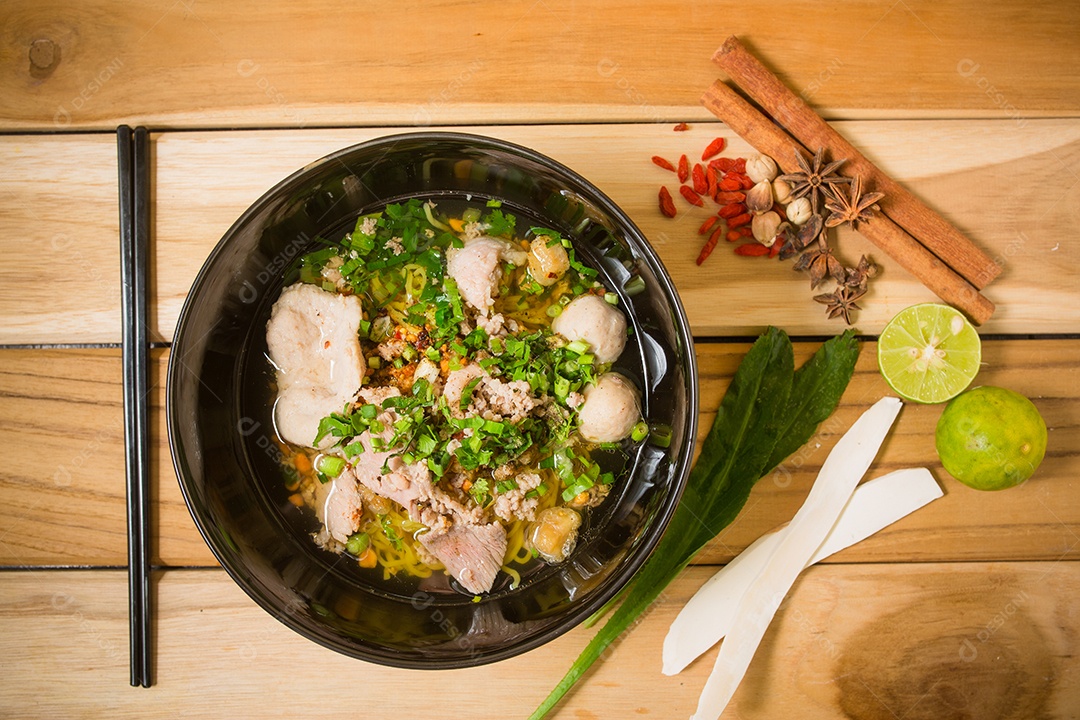 Tigela de macarrão com legumes e ovo cozido na mesa de madeira.