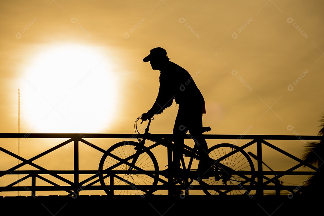 Silhueta de motociclista na ponte e pôr do sol.
