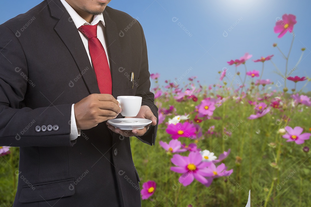 Homem no jardim com café na xícara branca.