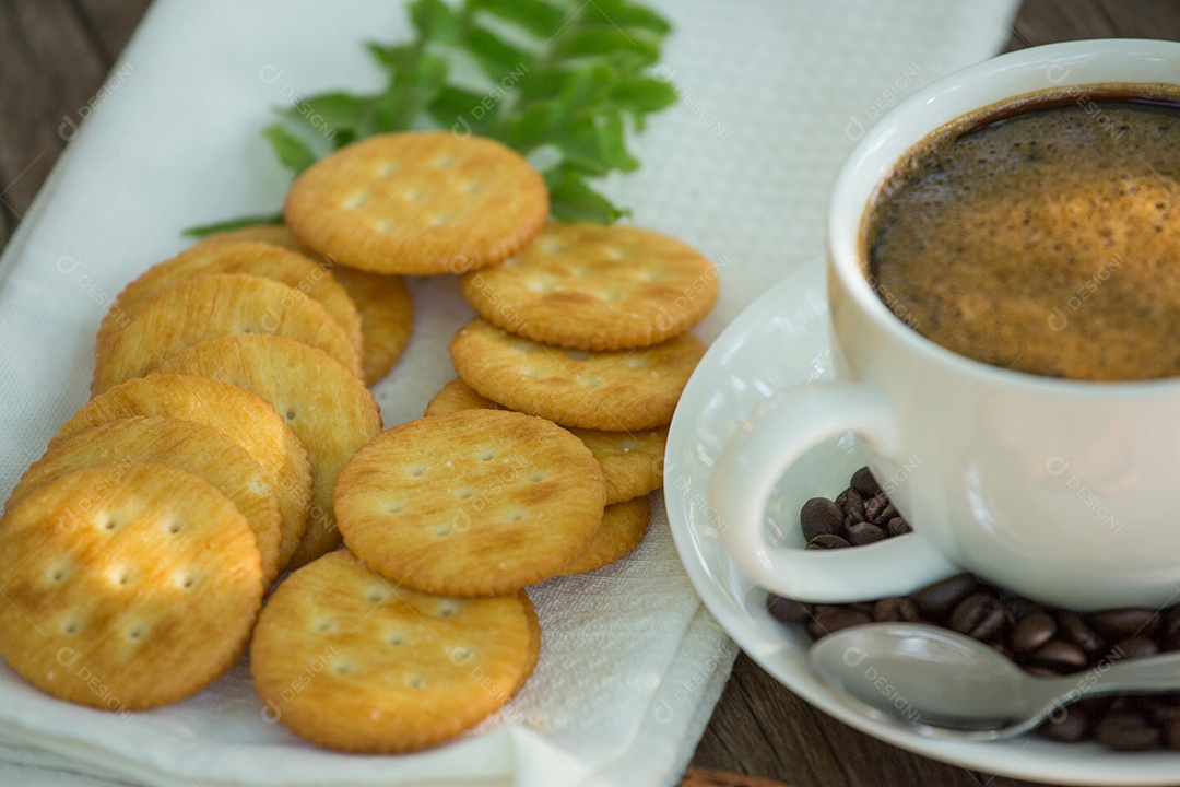 Xícara de café em uma tábua de madeira e biscoitos.