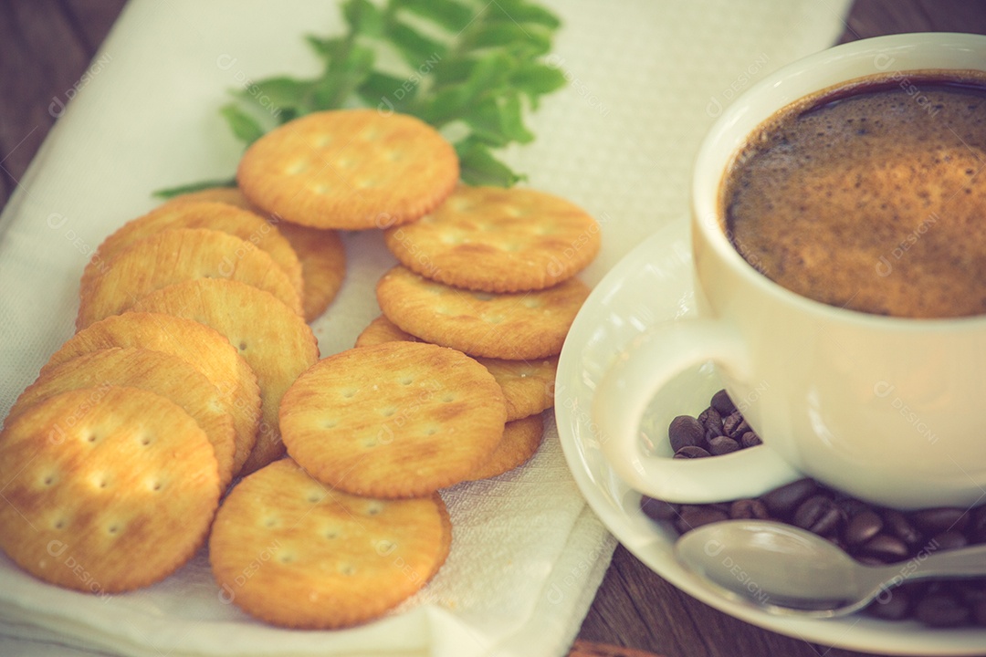 Xícara de café em uma tábua de madeira e cor vintage de biscoitos.