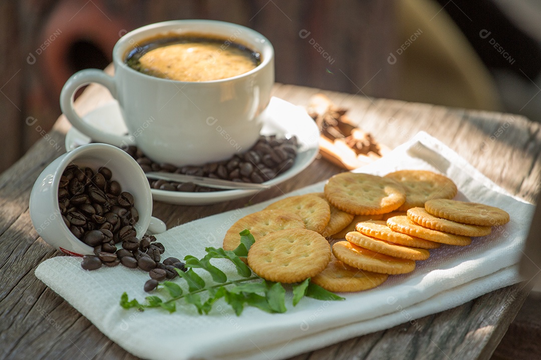 Xícara de café em uma tábua de madeira e biscoitos.