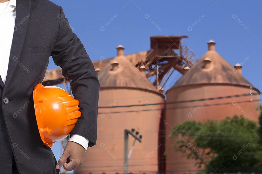 Engenheiro e fábrica industrial segurando capacete