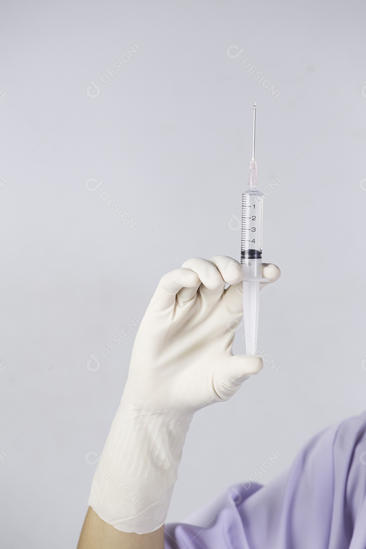 As mãos do médico segurando a seringa em close-up no fundo branco.