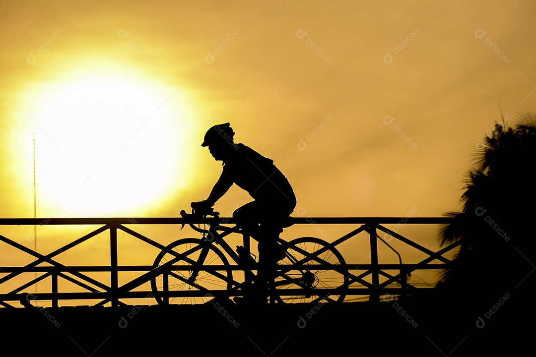 Silhueta de motociclista na ponte e pôr do sol