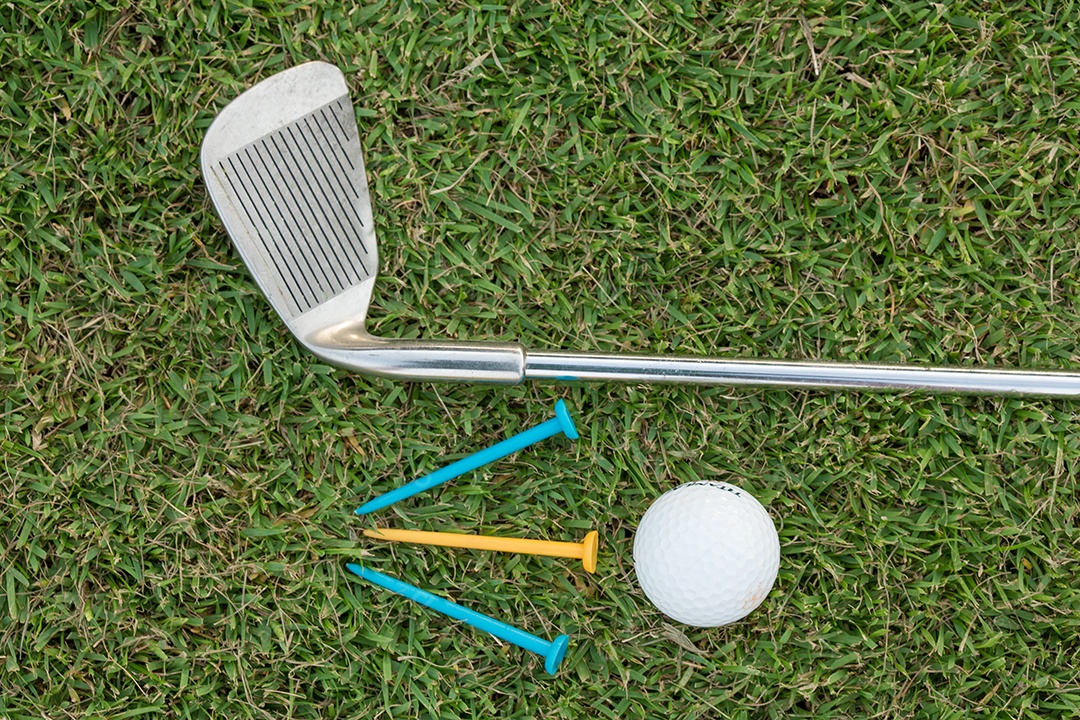 Bola de golfe e clube de golfe na grama
