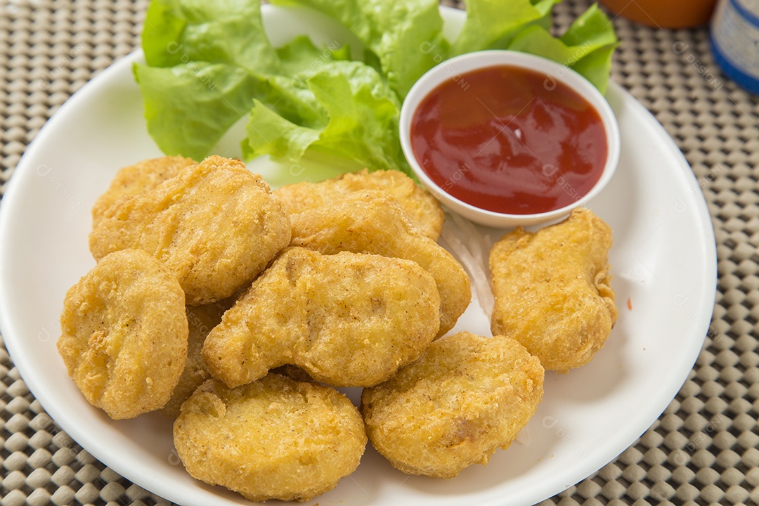 Pilha de nuggets de frango na chapa branca com molho