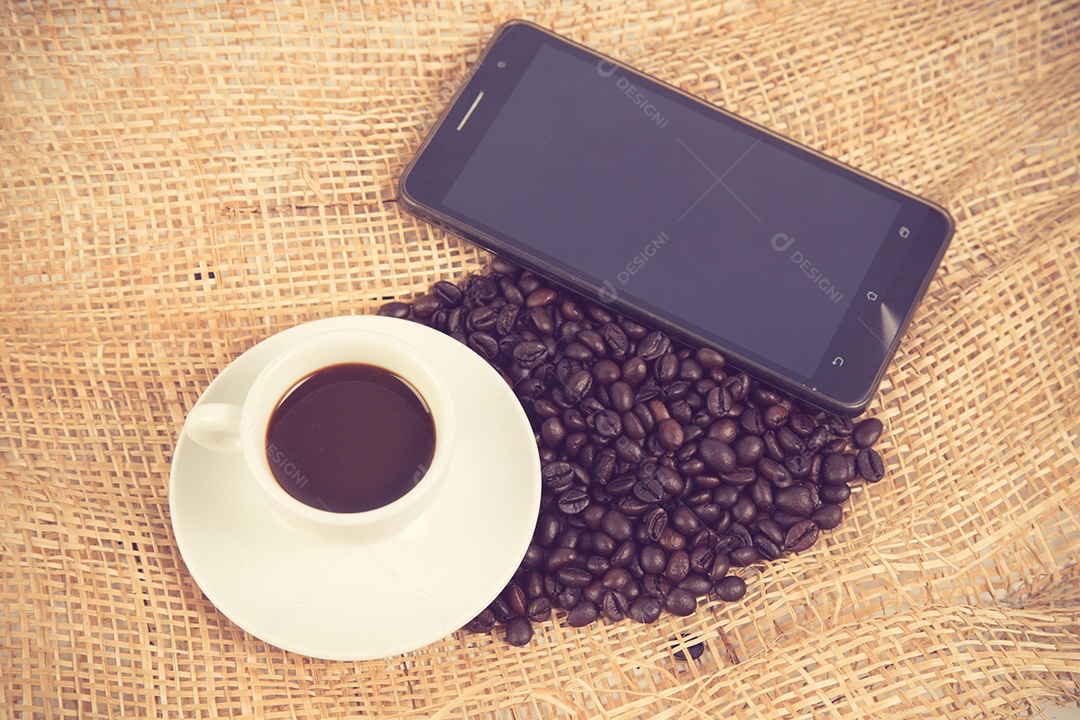 Xícara de café e feijão em um fundo branco.