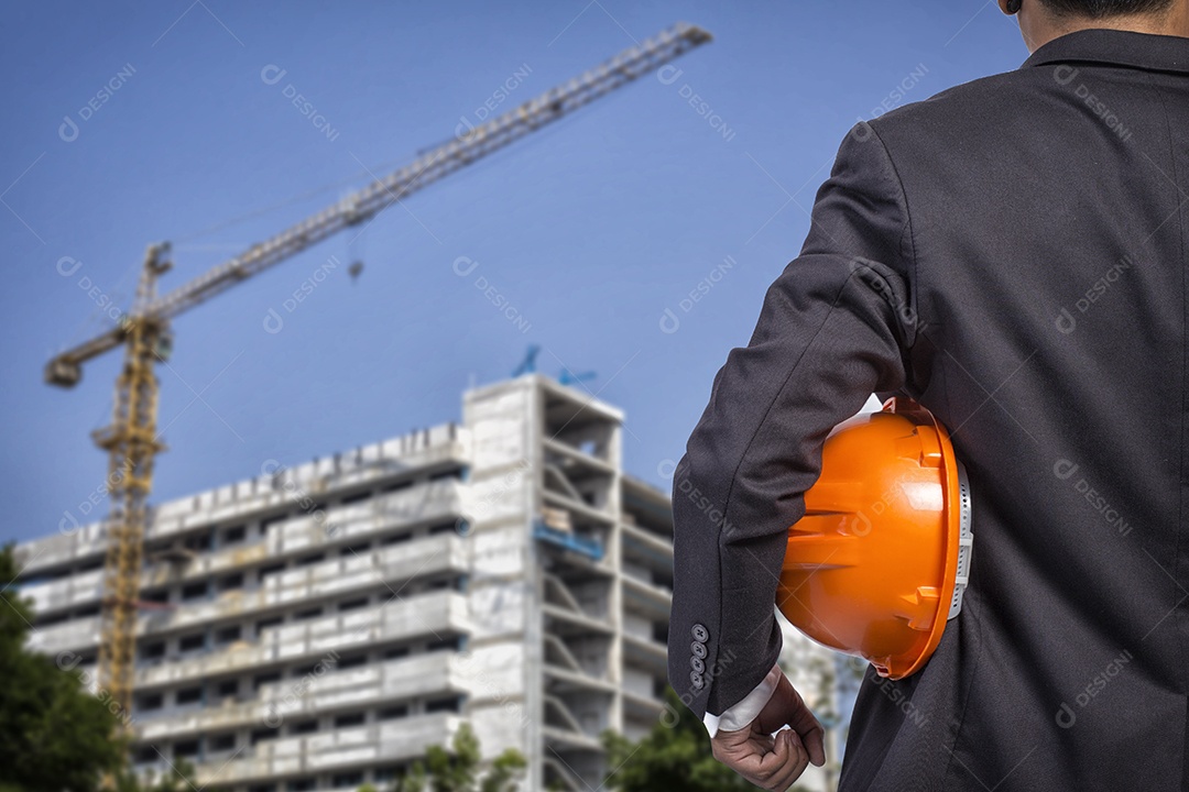 Engenheiro segurando capacete laranja para segurança dos trabalhadores na construção.