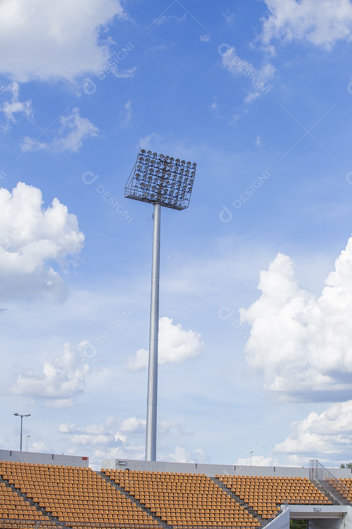 Torre de iluminação de grandes holofotes em um estádio de arena esportiva atrás do céu.