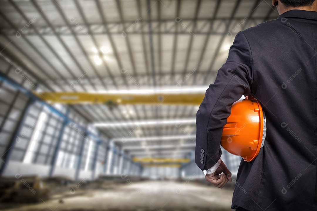 Engenheiro segurando capacete laranja para segurança dos trabalhadores na fábrica.