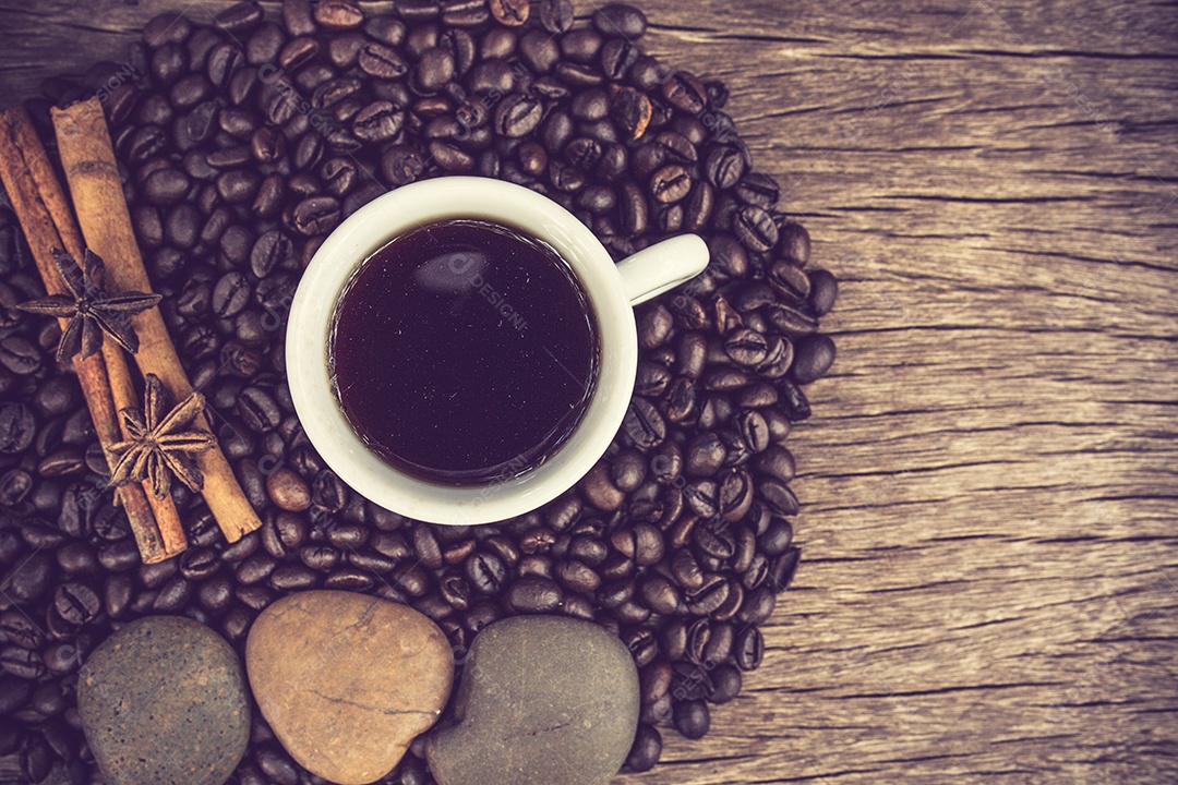 Xícara de café e grãos de café em uma mesa de madeira.